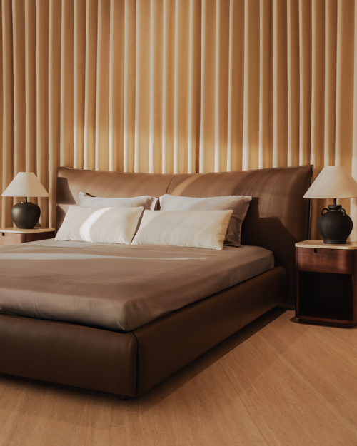 Brown bed with matching headboard against a wooden paneled wall.