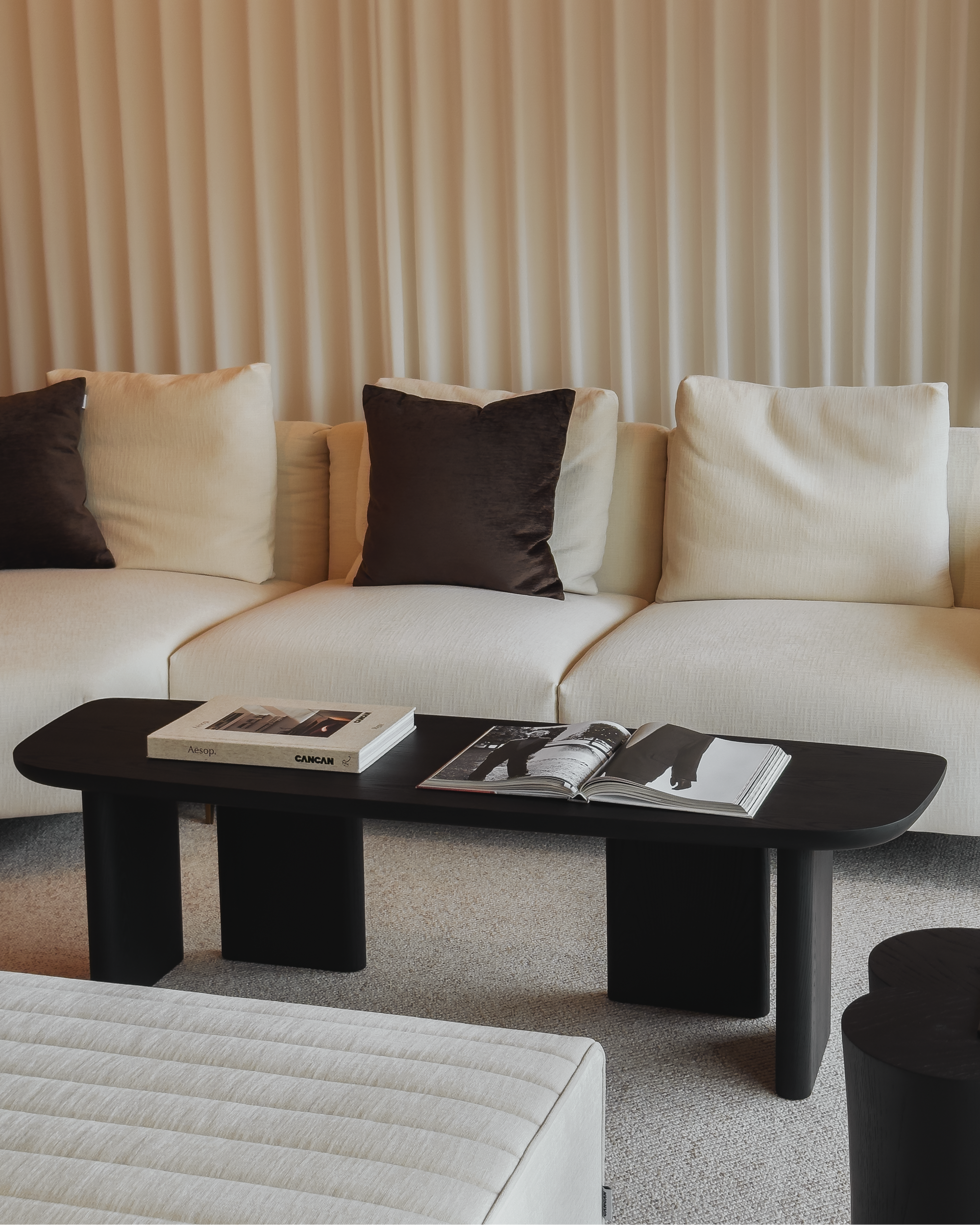 Modern living room with a beige sofa, black coffee table, and decorative items.