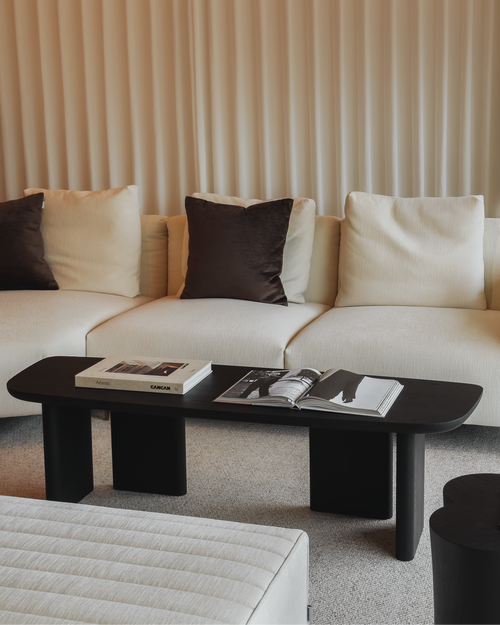 Modern living room with a beige sofa, black coffee table, and decorative items.