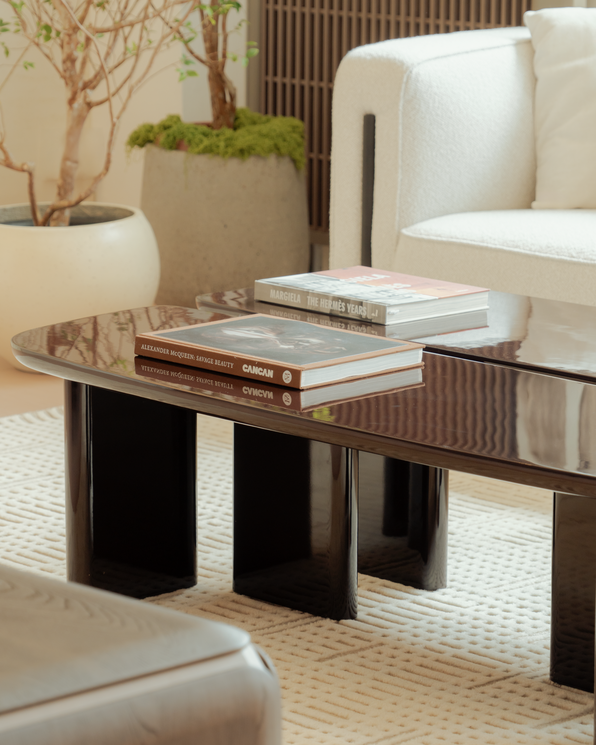 Modern living room with a glass coffee table, books, and a white sofa.