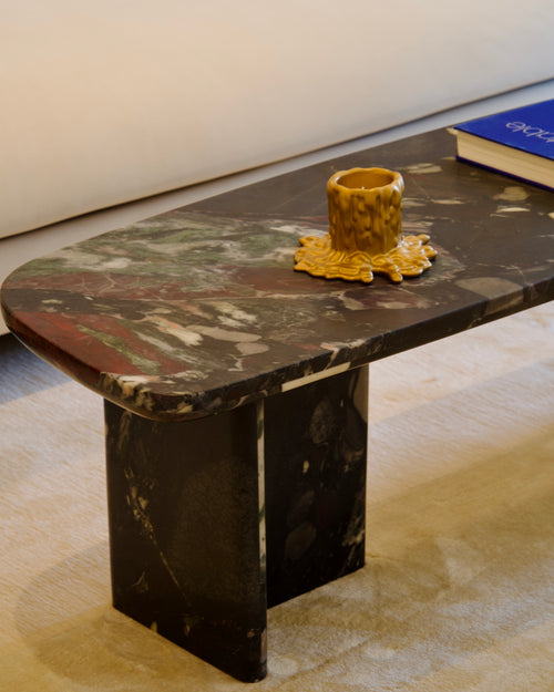 Marble coffee table with a decorative candle holder on a light-colored floor.