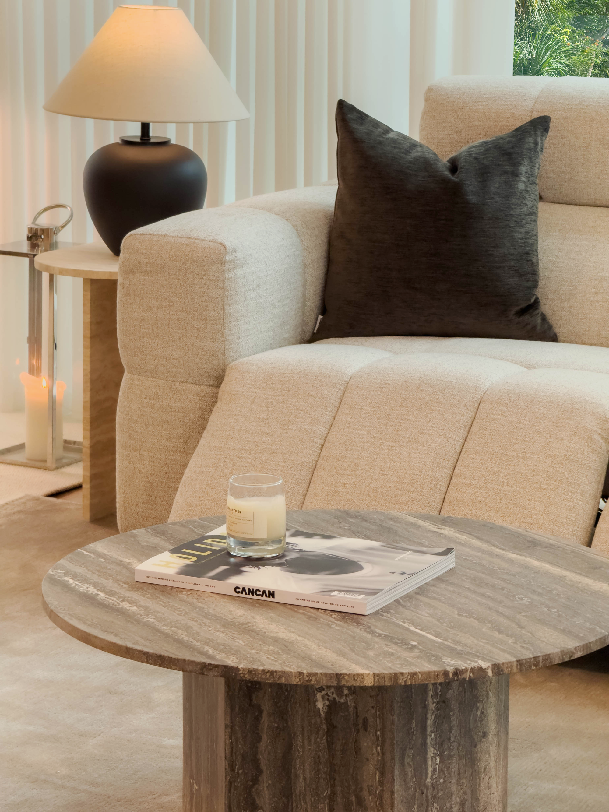 Beige sofa with a brown pillow and a wooden coffee table with a glass of milk and magazine.