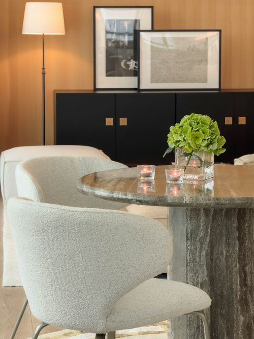 Modern dining room with marble table, chairs, and decorative elements.