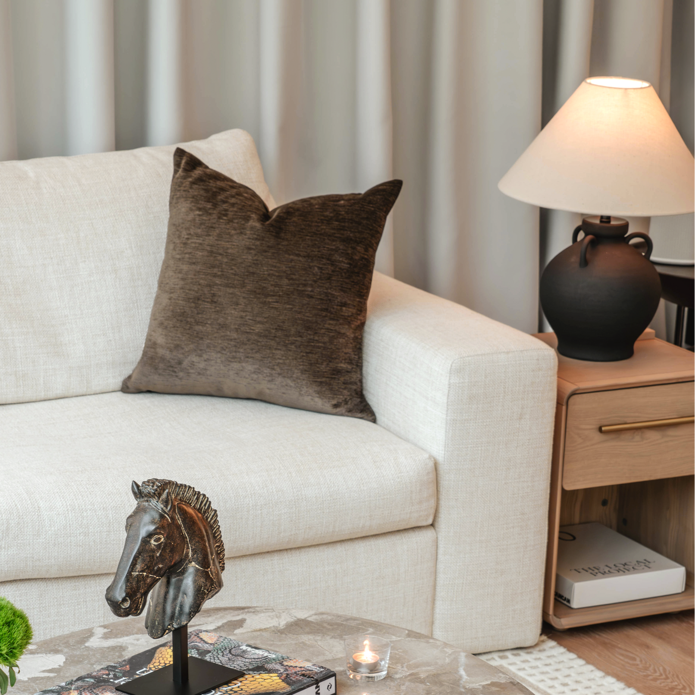 Living room with a beige sofa, marble coffee table, and decorative items.