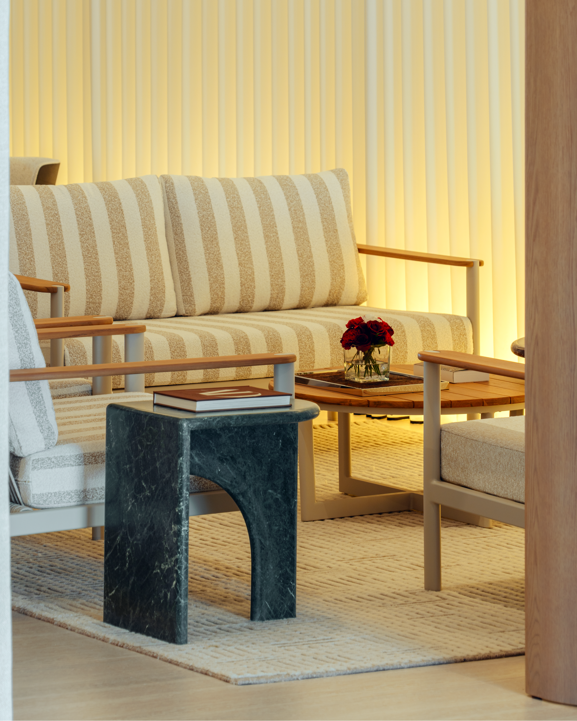 Modern living room with striped sofa, marble side table, and coffee table with flowers.