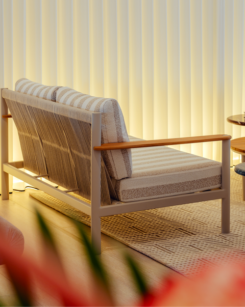 Wicker chair with cushions against a light curtain background
