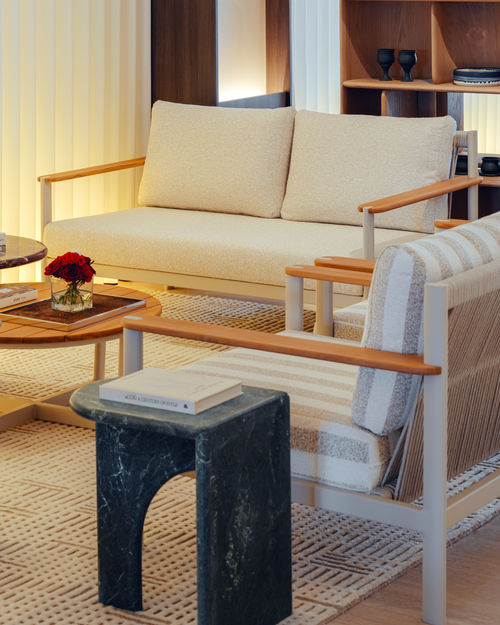 Modern living room with beige sofa, striped armchair, and marble side table.
