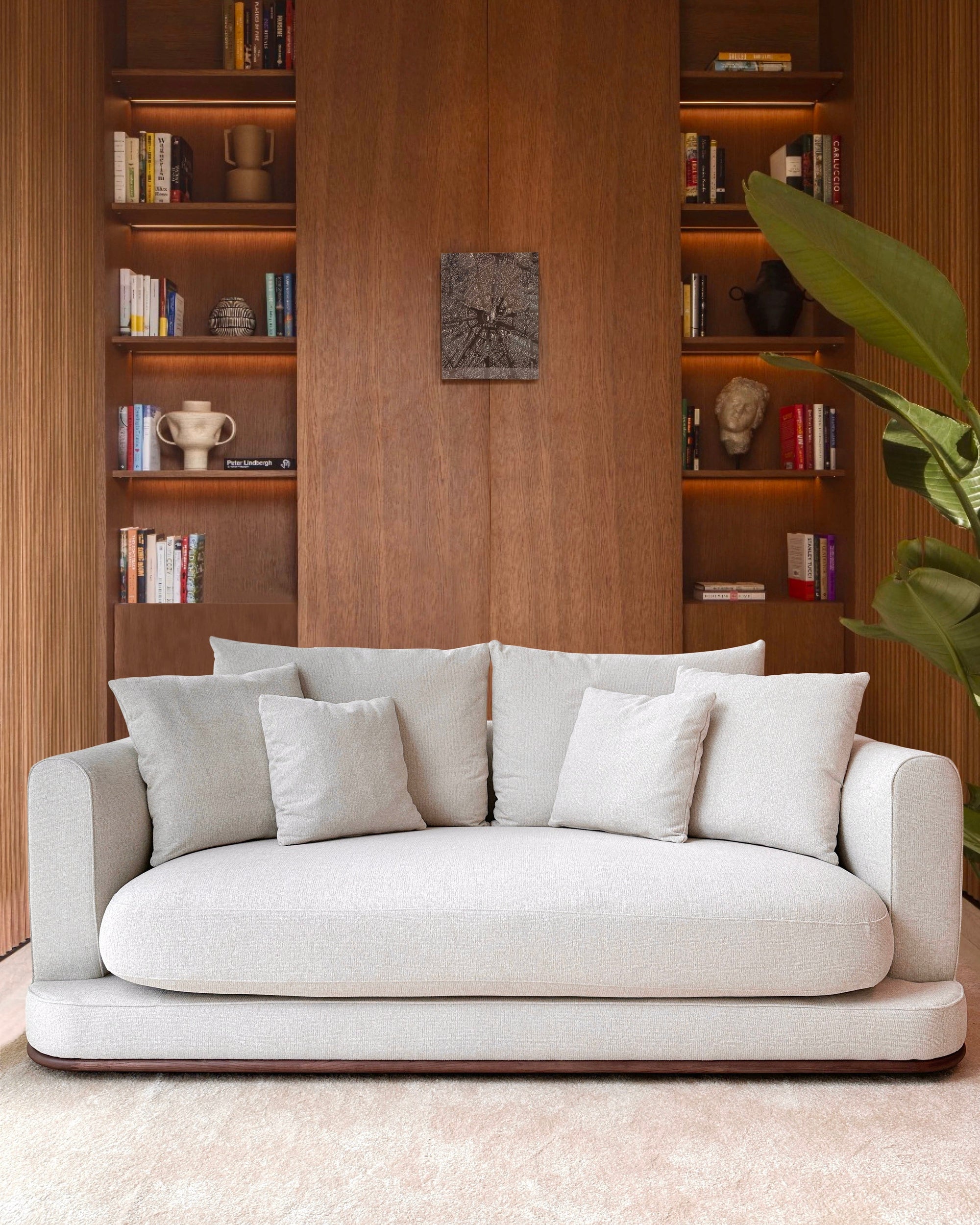 White sofa in a room with wooden bookshelves and decor.