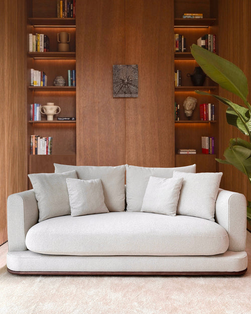 White sofa in a room with wooden bookshelves and decor.
