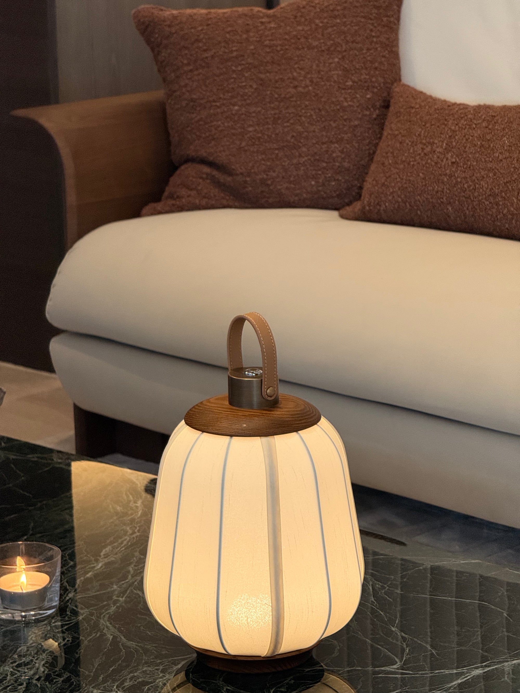 Decorative lamp on a marble surface with a couch and pillows in the background