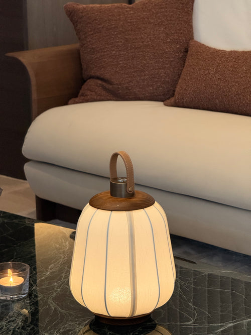 Decorative lamp on a marble surface with a couch and pillows in the background
