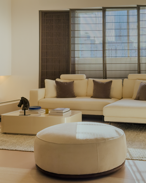 Modern living room with beige sectional sofa and ottoman.