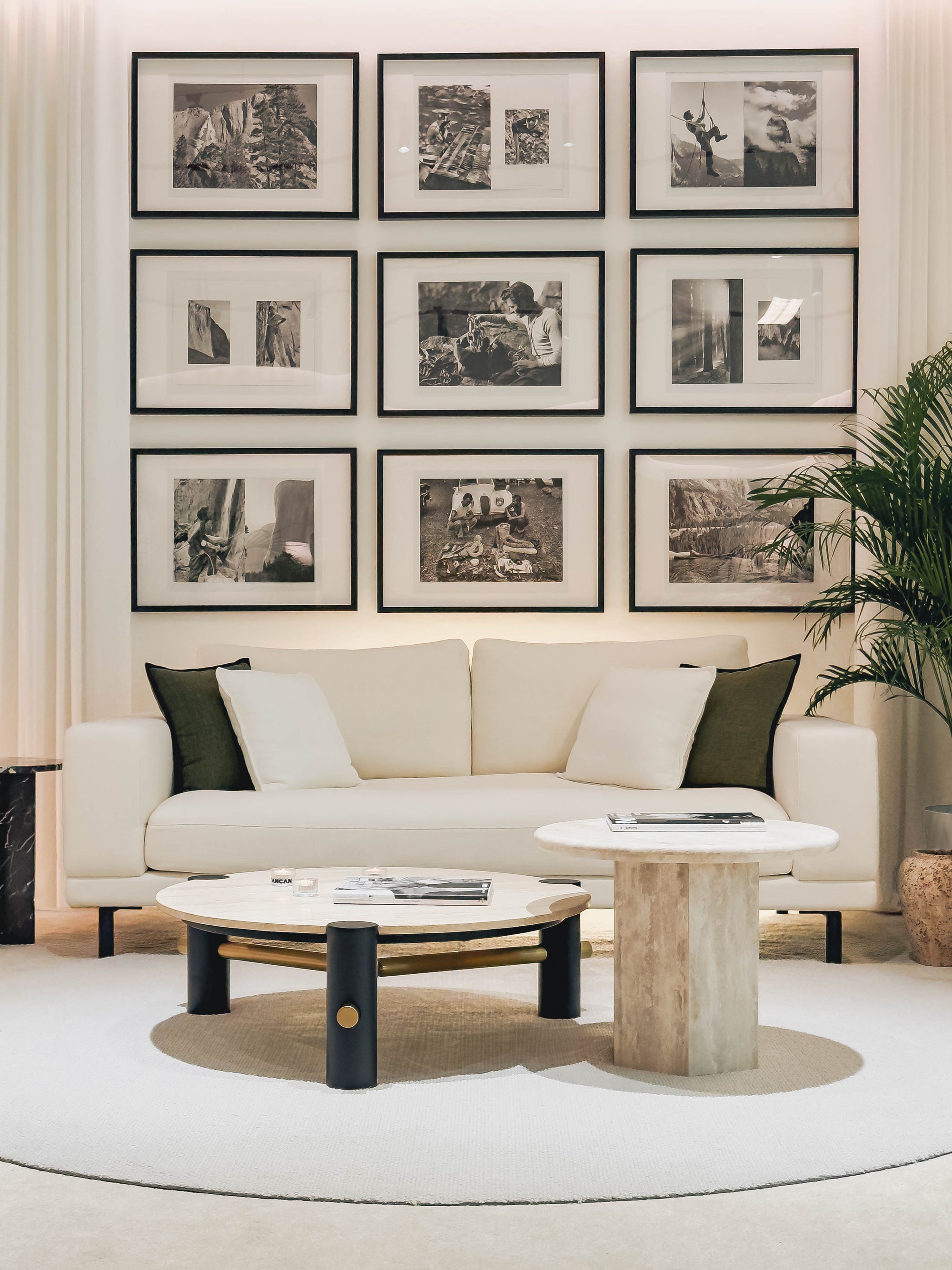 Modern living room with a beige sofa, round coffee table, and framed black and white photos on the wall.