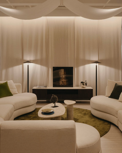 Modern living room with white furniture, a TV, and decorative items.