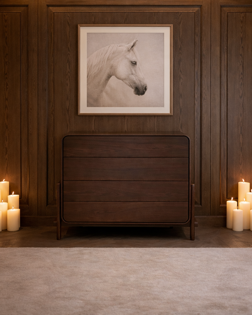 Wooden dresser with candles on either side against a wooden wall with a horse portrait.