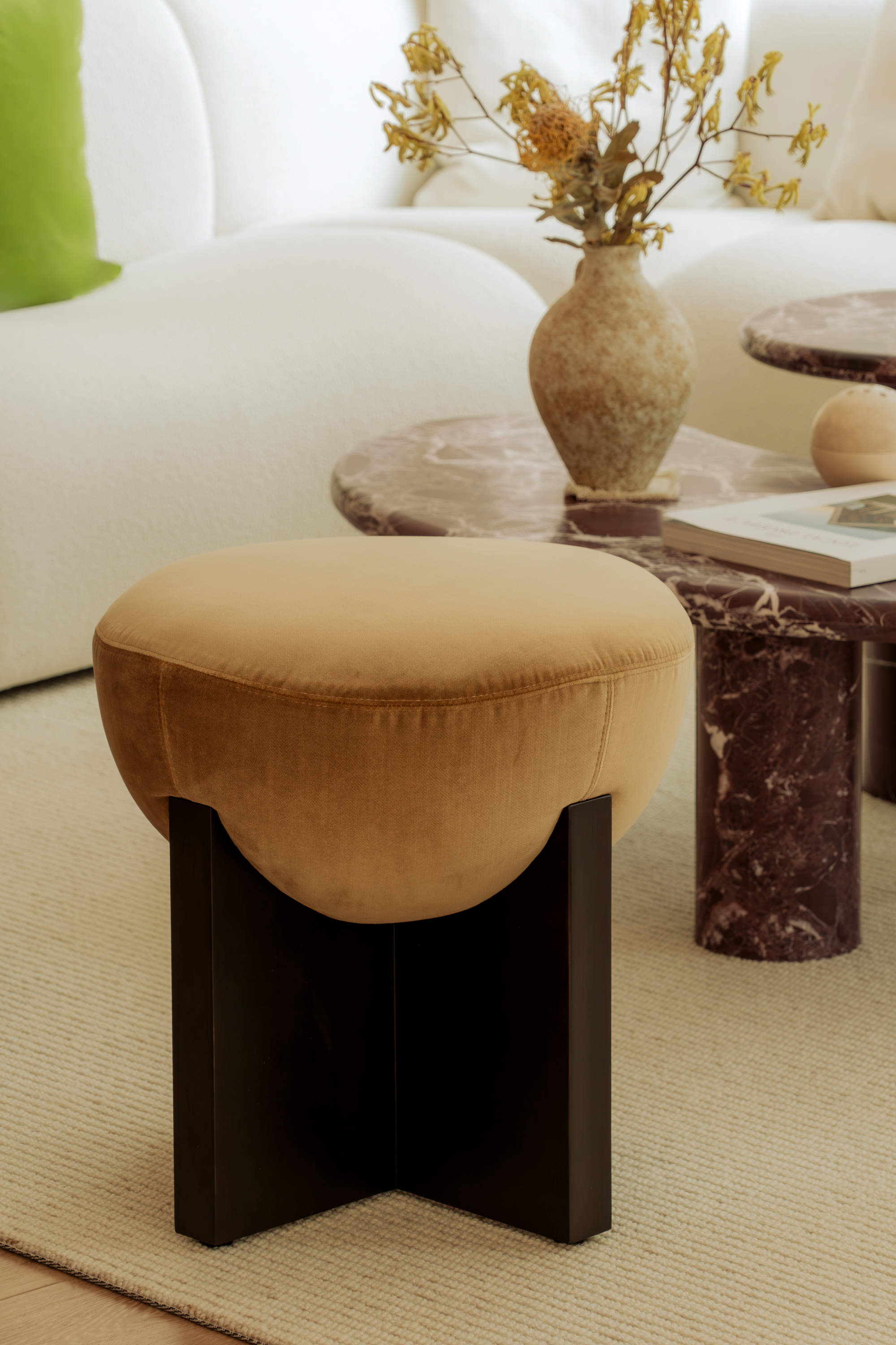 Brown ottoman in a living room setting with a vase and books on a table.