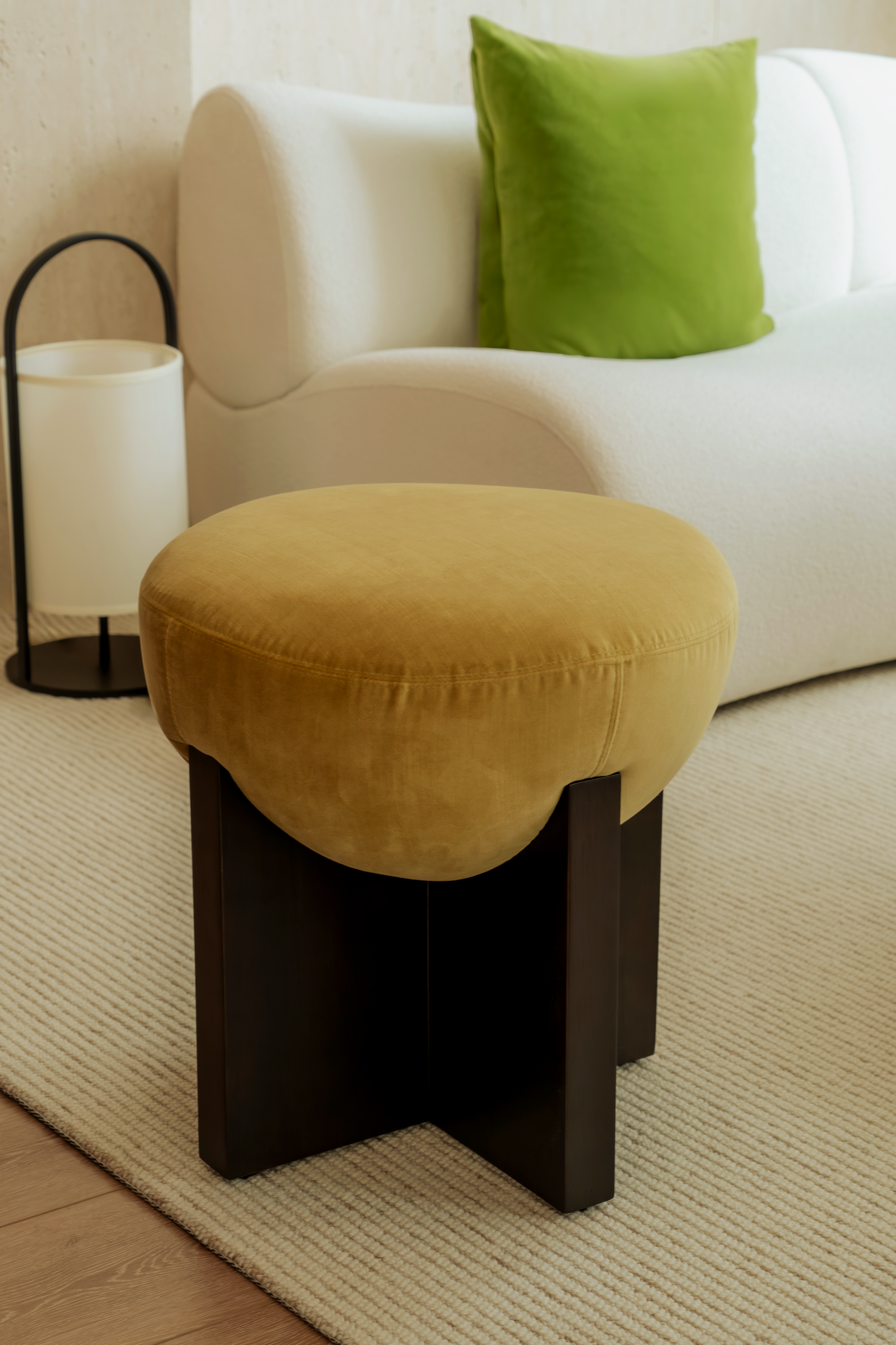 Yellow cushioned stool in front of a white sofa with a green pillow
