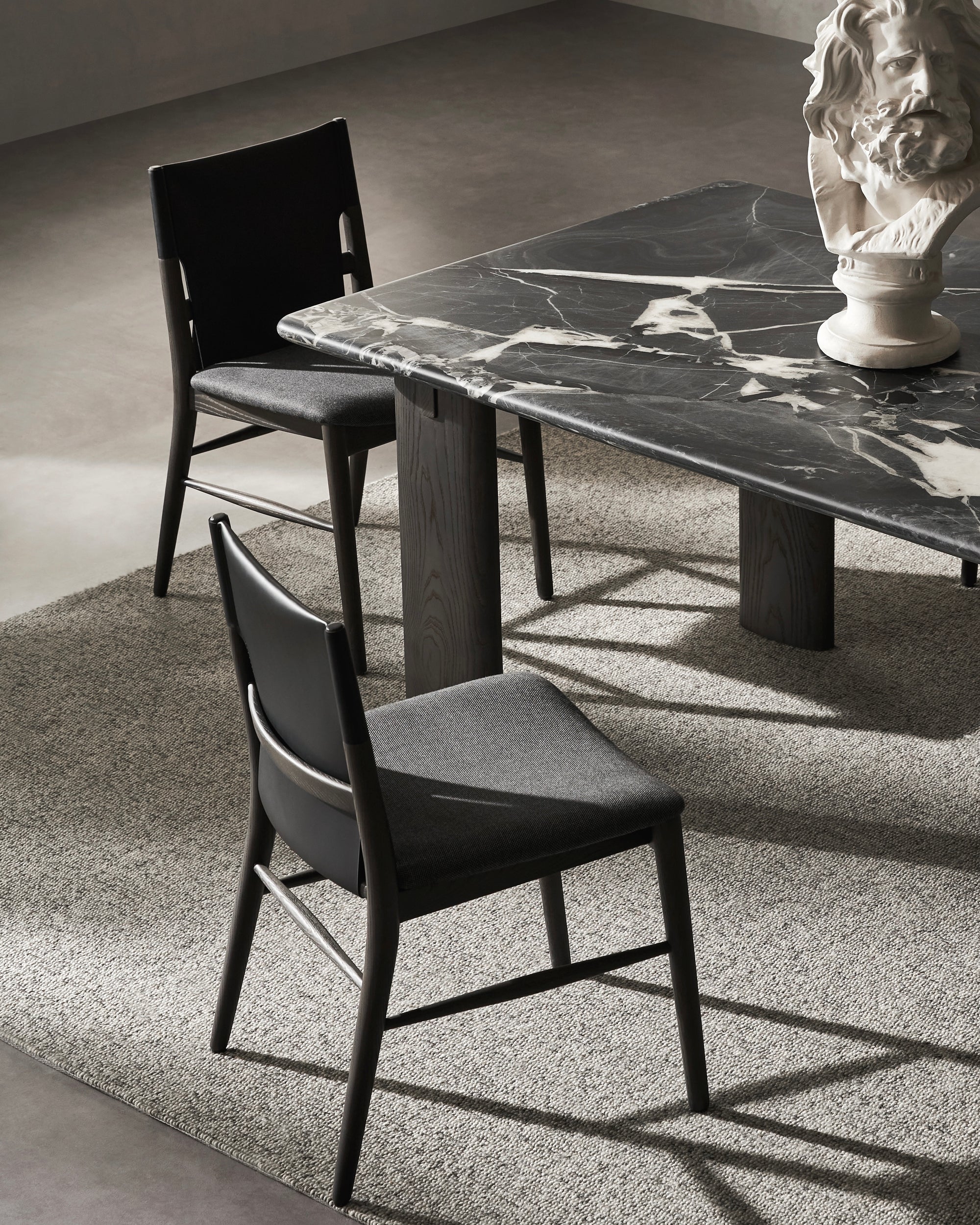 Dining table with marble surface and two chairs in a room setting.