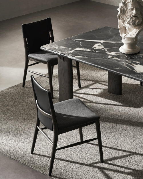 Dining table with marble surface and two chairs in a room setting.