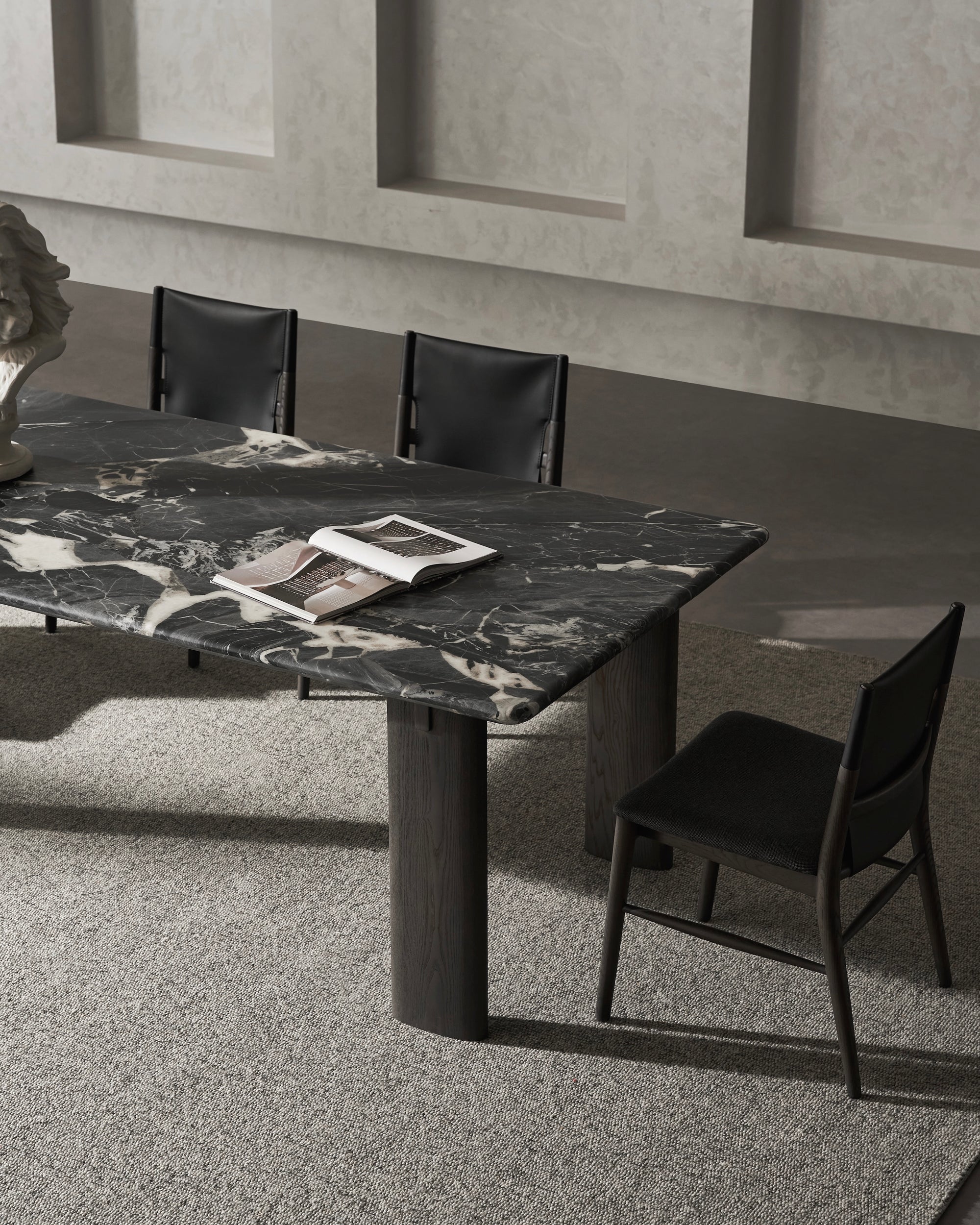 Marble dining table with black chairs in a modern interior setting.