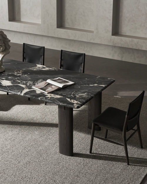 Marble dining table with black chairs in a modern interior setting.