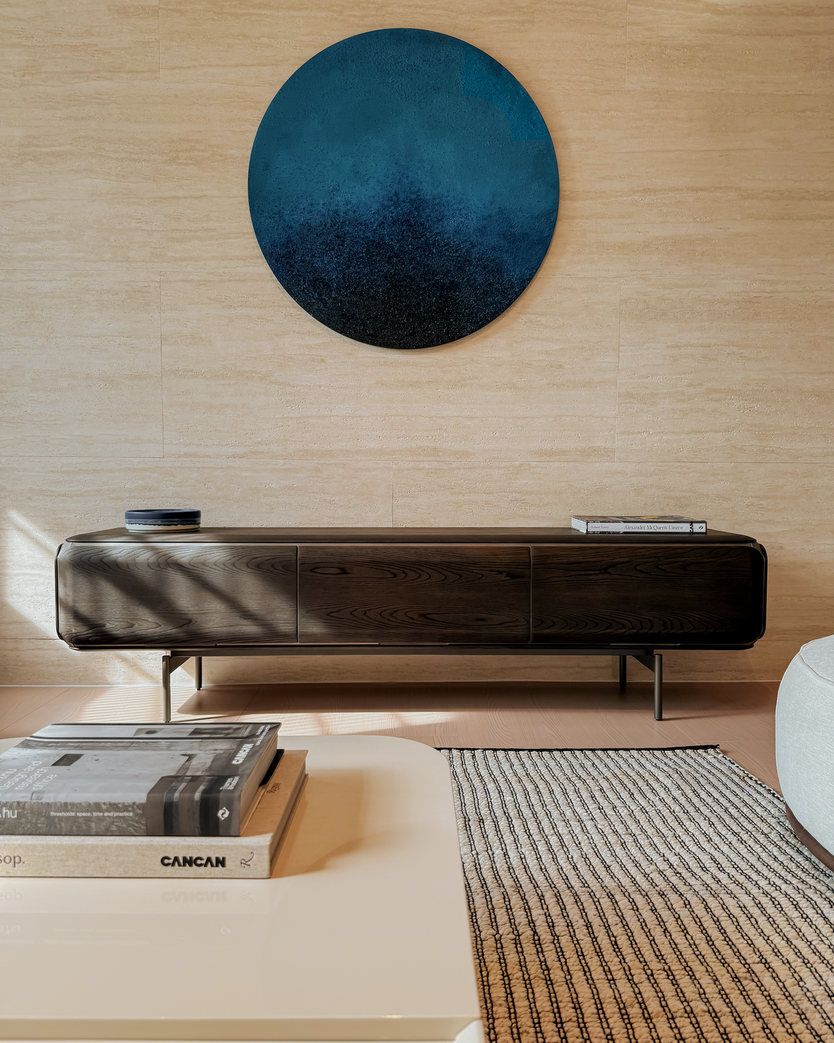 Modern interior with a long dark console table against a wooden wall, featuring a round blue artwork.