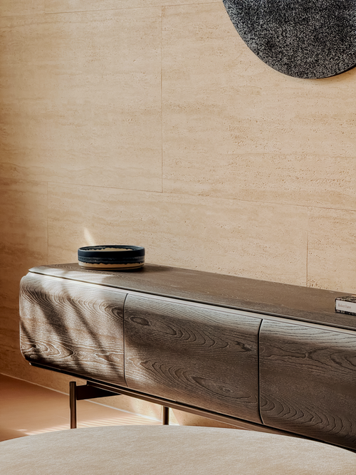 Wooden console table with decorative bowl against a beige wall