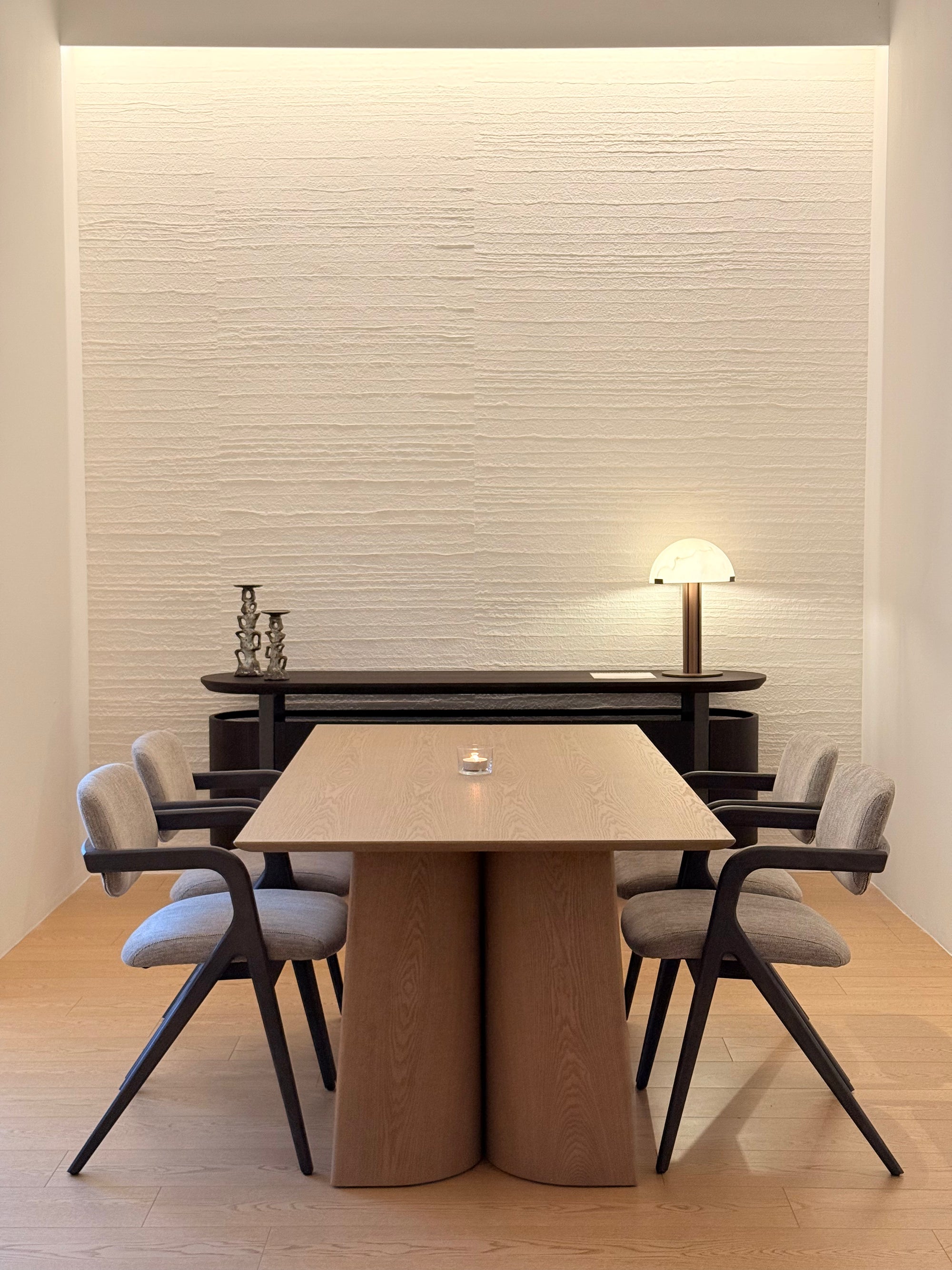 Modern dining room with a wooden table and chairs against a textured wall.