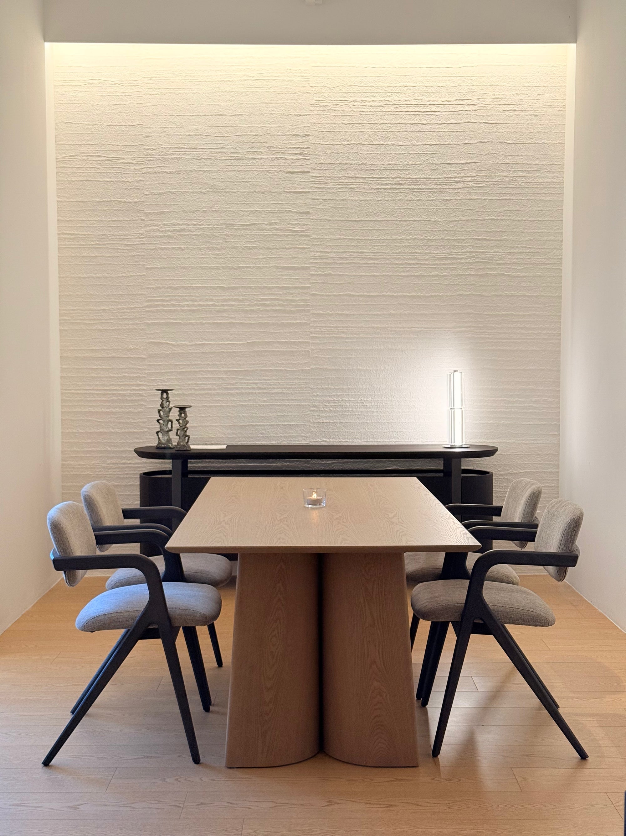 Modern dining room with a wooden table and chairs against a textured wall.