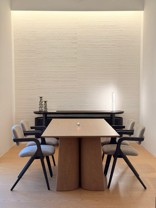Modern dining room with a wooden table and chairs against a textured wall.