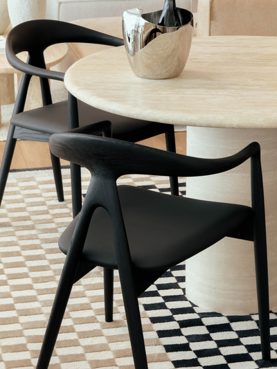Black chairs around a round marble table in a stylish room.