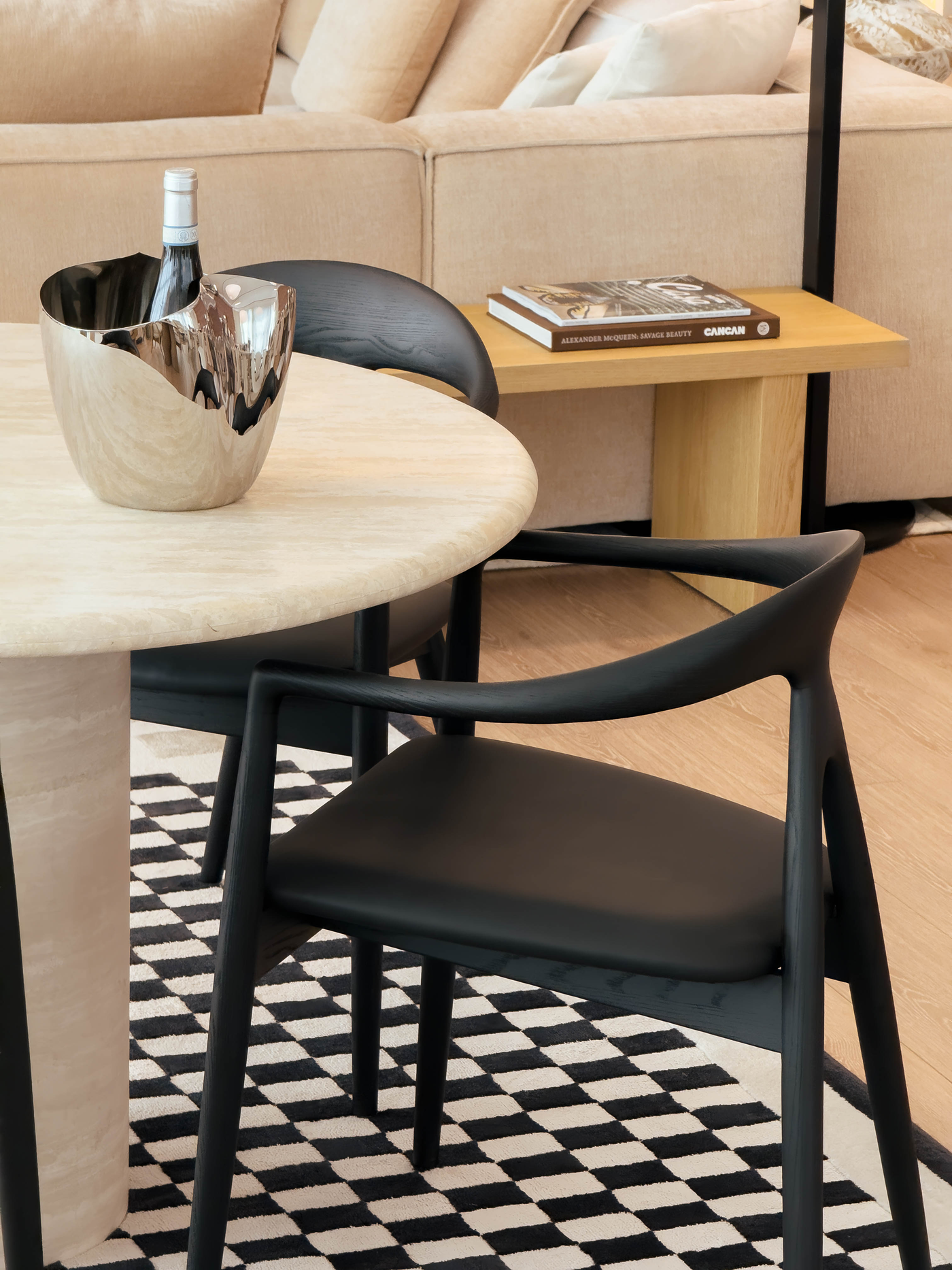 Black chairs around a round table with a bottle and book in a living room setting.