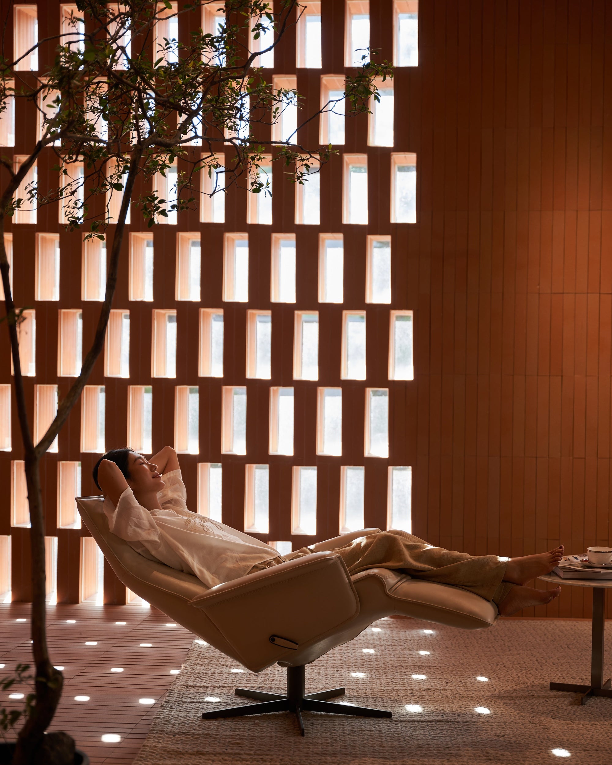 Person relaxing in a modern chair with a wooden wall and plant in the background