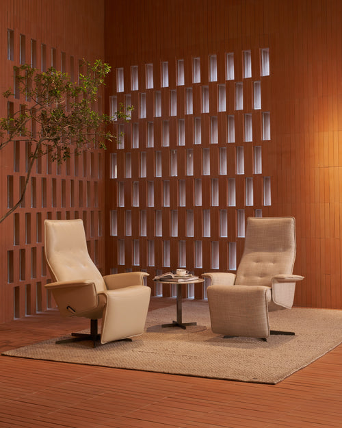 Two beige recliner chairs in a room with wooden walls and a small table.